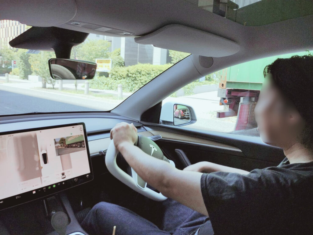 テスラで受けるペーパードライバー講習|東京ドライビングサポート ペーパードライバー講習でテスラを運転する受講者。タッチパネル式ディスプレイにルートと周囲の車両が表示されている。