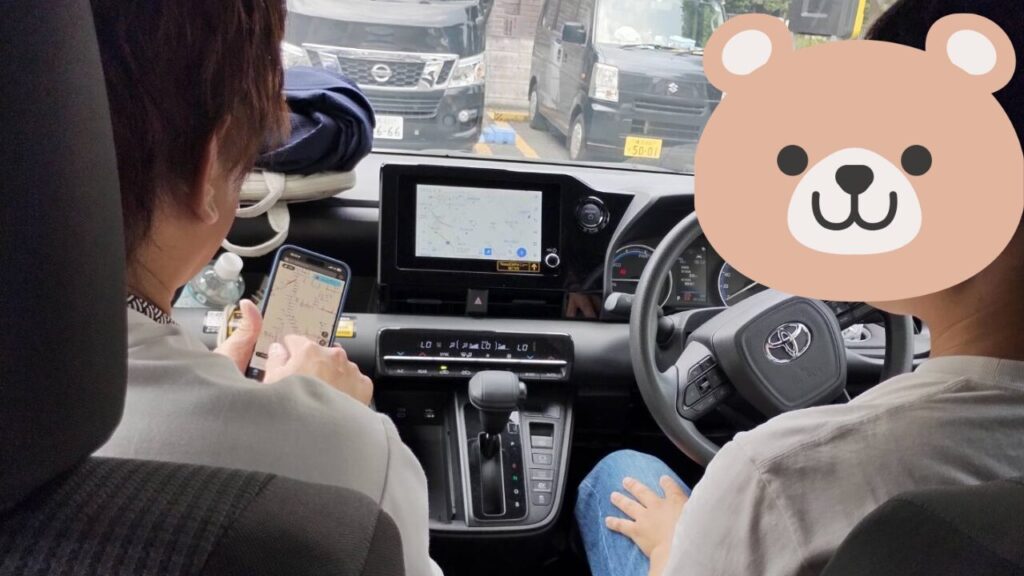 運転講習中の後部座席からの視点|東京ドライビングサポートの現場風景 東京ドライビングサポートのペーパードライバー講習中、40代男性がインストラクターとともに車内でルート確認を行う様子。都内での運転練習風景。
