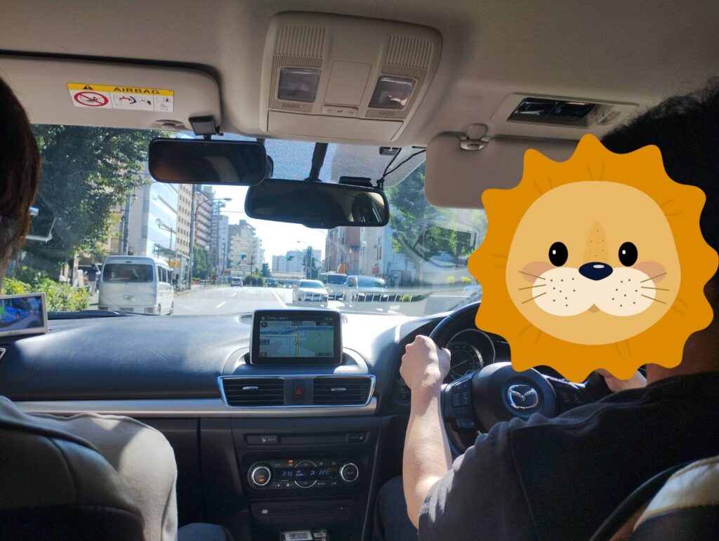 東京ドライビングサポートのペーパードライバー講習で運転中の30代男性。マツダ車での教習風景を後部座席から撮影。