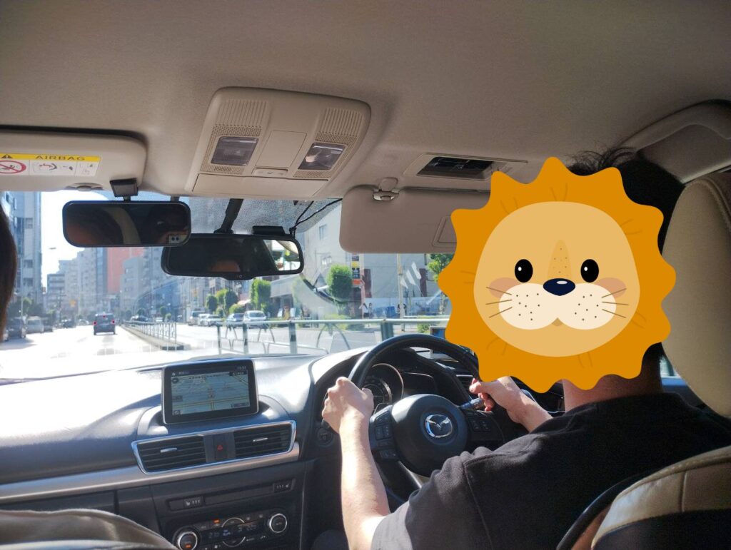 ペーパードライバー講習中の運転風景｜東京都内の市街地で走行する男性受講者の後ろ姿